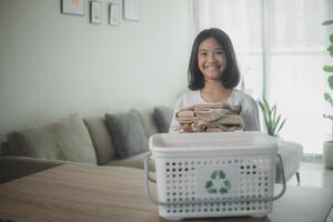 reciclar ropa concepto. asiático pequeño niña con un reciclaje caja lleno de ropa. foto