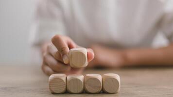 Businesswomen stack blank wooden cubes on the table with copy space, empty wooden cubes for input wording, and an infographic icon. photo