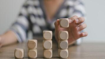 Businesswomen stack blank wooden cubes on the table with copy space, empty wooden cubes for input wording, and an infographic icon. photo