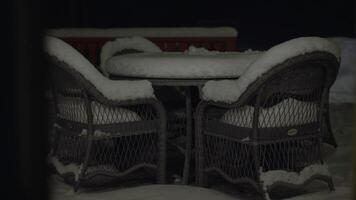 garden table and chairs covered with snow. video