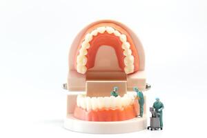 Miniature people , Dentist repairing human teeth with gums and enamel photo