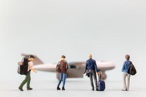 Miniature people, travelers embarks on a delightful vacation, gleefully boarding a tiny airplane photo