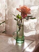 un Rosa en un florero en un mesa foto