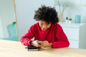 African girl holding smartphone touch screen typing scroll page at home. Woman with cell phone surfing internet using social media apps playing game. Shopping online Internet news cellphone addiction photo