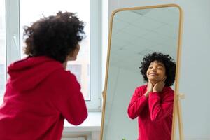 Love yourself. Beautiful young smiling african american woman dancing enjoying her mirror reflection. Black lady looking at mirror looking confident and happy. Self love concept photo