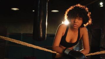 Woman fighter girl power. African american woman fighter with boxing gloves standing on boxing ring leaning on ropes waiting and resting. Strong powerful girl. Strength fit body workout training photo