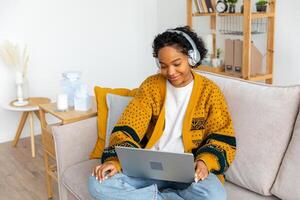 africano americano niña utilizando ordenador portátil a hogar oficina mirando a pantalla mecanografía chateando leyendo escritura correo electrónico. joven mujer teniendo virtual reunión en línea charla vídeo llamada conferencia. trabajo aprendizaje desde hogar foto