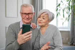 Video call. Happy senior couple woman man with smartphone having video call. Mature old grandmother grandfather talking speaking online. Older generation modern tech usage. Virtual meeting online chat photo