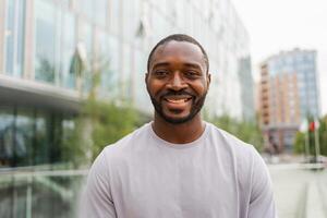 Happy african american man smiling outdoor. Portrait of young happy man on street in city. Cheerful joyful handsome person guy looking at camera. Freedom happiness carefree happy people concept photo