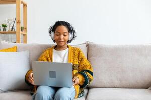 africano americano niña utilizando ordenador portátil a hogar oficina mirando a pantalla mecanografía chateando leyendo escritura correo electrónico. joven mujer teniendo virtual reunión en línea charla vídeo llamada conferencia. trabajo aprendizaje desde hogar foto