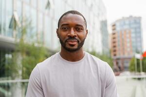 contento africano americano hombre sonriente exterior. retrato de joven contento hombre en calle en ciudad. alegre alegre hermoso persona chico mirando a cámara. libertad felicidad despreocupado contento personas concepto foto