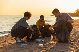 tierra día. voluntarios activistas equipo recoge basura limpieza de playa costero zona. mujer mans pone el plastico basura en basura bolso en Oceano costa. ambiental conservación costero zona limpieza foto