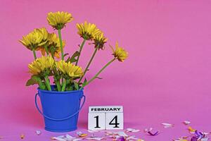 Yellow dahlia flower with wooden block cube on pink background. photo