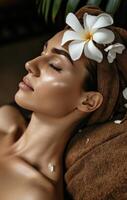 AI generated young woman has brown towel and white flower in her hair from traditional spa photo