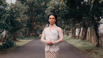 Elegant person in traditional attire standing on a tree-lined path video