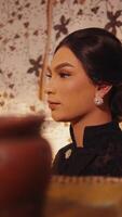 Elegant woman with vintage makeup and hairstyle, profile view, with warm ambient lighting and floral background. video