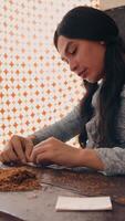 Focused craftsperson working on a project with tools on a wooden table, with a patterned backdrop video