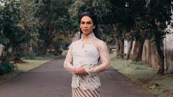 Elegant person in traditional attire posing on a serene pathway with trees. video