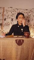 Vintage-styled woman writing at desk with thoughtful expression, retro wallpaper background video