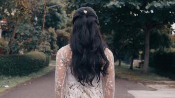 Rear view of a woman with long hair walking in a park, symbolizing solitude and contemplation. video