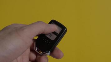 Hand of man holding and pressing car key remote. Hand holds car keys on a clear screen background. Copy space. Concept car rental driving transport automotive. Thumb pressing button of car remote key video
