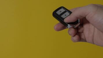 Hand of man holding and pressing car key remote. Hand holds car keys on a clear screen background. Copy space. Concept car rental driving transport automotive. Thumb pressing button of car remote key video