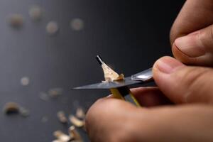 Hands sharpening pencil using utility knife, close up. photo