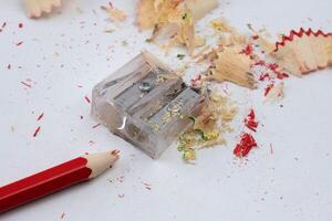 Colored pencils or pencils and sharpener isolated on white background. Red wooden pencil and pencil shavings on white table. photo