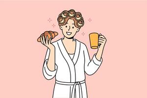 Woman enjoys morning breakfast of fresh croissant and cup coffee, standing in bathrobe and curlers vector