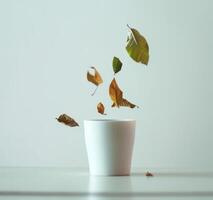 AI generated a white cup with leaves falling from it photo