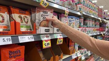 23.10.23 Mississauga Canada -Selection of rice in the store. Discounted rice on a store counter. A European woman in a supermarket chooses brown rice and Jasmine rice. video