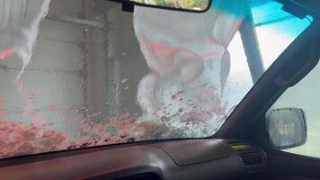 visie van een automatisch auto voorruit wassen met schuim automatisch auto wassen visie van de auto cabine. glijden schuim van de voorruit. visie van binnen. tijd naar wassen de auto. video