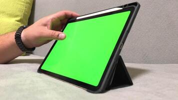 uomo a casa con tavoletta computer con verde schermo. video di verde smartphone schermo modello. selezione di acquisti nel un in linea negozio. stagione di sconti e regalo acquisti.