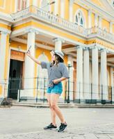 Beautiful tourist in hat taking selfie in the cathedral of Granada. Young travel woman taking a selfie in a public square photo