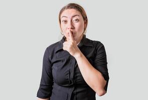 Amazed woman making silence gesture with finger. Blonde girl making silence gesture isolated photo