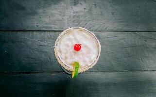 Top view of delicious frozen coconut cocktail with cherry. Coconut margarita with cherry on wooden table photo