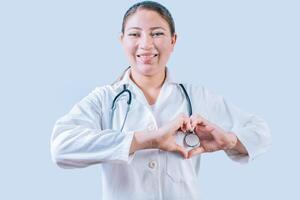 Smiling doctor making heart shape on isolated background. Friendly female doctor making heart gesture with hands isolated photo