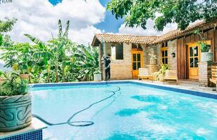 piscina mantenimiento y limpieza con vacío manguera. hombre limpieza un hermosa nadando piscina con un succión manguera foto