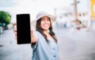 Tourist girl showing cell phone screen on the street. Travel woman showing cell phone screen on the street photo