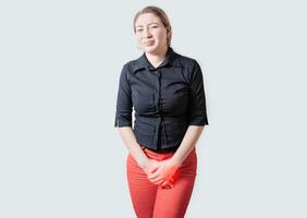 Young woman suffering with urinary problems isolated. Girl with hands on crotch with urinary problems photo