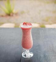 Strawberry milkshake on wooden table with blurred background. Close up of healthy strawberry smoothie on wood with blurred background, Strawberry smoothie on wooden table. photo