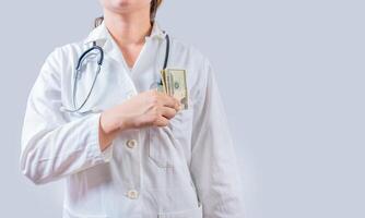 Unrecognizable doctor putting bribe money in pocket isolated. Dishonest female doctor putting money in pocket. Medical bribery concept photo