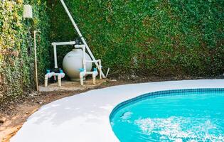 Pool pump with sand filter installed near of swimming pool. Home swimming pool filter and treatment plant installed. Pool purification and maintenance system photo