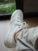 white canvas shoes on green and wooden backgrjound classic style easy and smooth life style photo