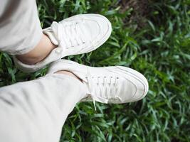 white canvas shoes on green and wooden backgrjound classic style easy and smooth life style photo