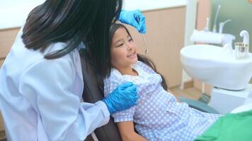 una piccola ragazza carina che ha i denti esaminati dal dentista in clinica dentale, controllo dei denti e concetto di denti sani video