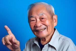 ai generado asiático abuelo mirando y sonriente con resucitado índice dedo en azul fondo, neural red generado Arte foto