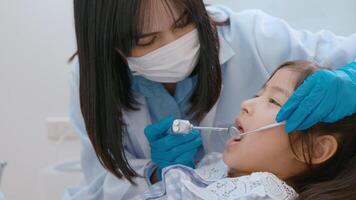 una piccola ragazza carina che ha i denti esaminati dal dentista in clinica dentale, controllo dei denti e concetto di denti sani video