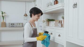 An Asian woman with cleaning gloves using alcohol spray sanitiser to cleaning house, healthy lifestyle concept video