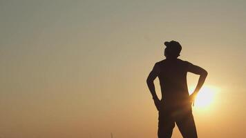 jovem homem esticam corpo preparar para cardio aquecer com sombra exercício às pôr do sol ar livre. video